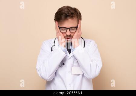 Young caucasian man doctor looking tired after work. Stock Photo