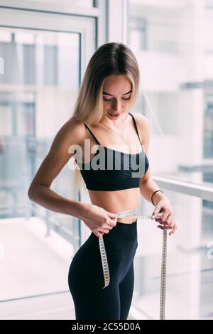 Woman measuring her waist with centimeter tape at home Stock Photo - Alamy