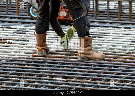 A construction worker braiding iron on a construction site. Only legs and arms are vissible. Stock Photo