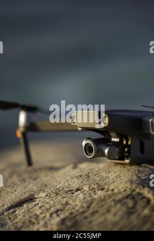 A closeup vertical shot of a drone with a camera on a rocky surface Stock Photo
