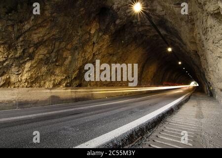 Road in a rock tunnel with traces of car lights. Movement concept Stock Photo
