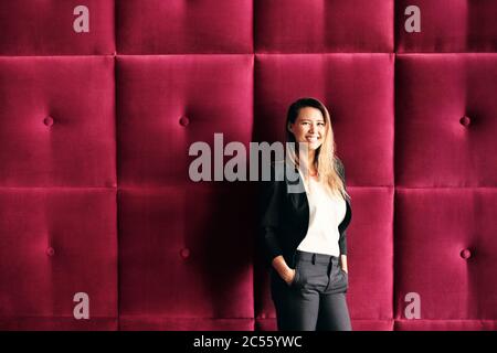 Young Business Woman Standing Against Burgundy Wall Panels Stock Photo