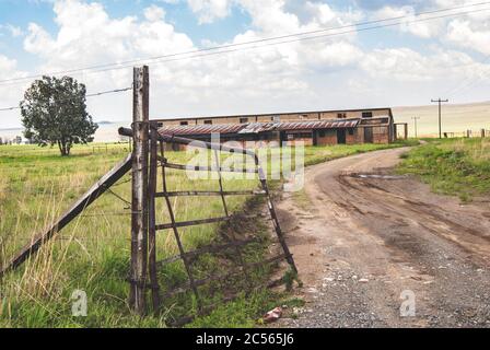 Entrance of an old farmland with weathered metal gates Stock Photo