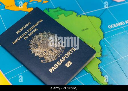 Top view of Brazilian passport over map. Focus on the South American continent. Emigration, travel, destination concept. Stock Photo