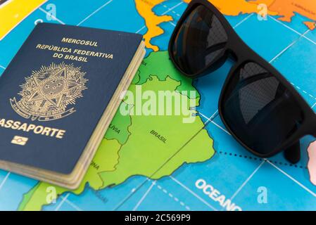 Top view of Brazilian passport over map. Focus on the South American continent. Emigration, travel, destination concept. Stock Photo