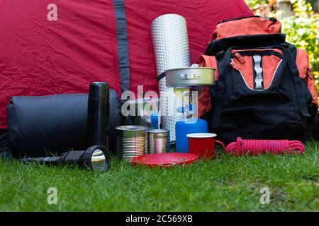 Picture of camping tools on the grass - backpack, tent, gas tank, cans, compass, etc - ready to go in the woods Stock Photo