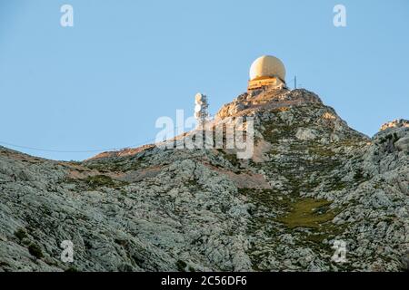 Radar dome station and radio antennas on top of a mountain at sunset. Aerial surveillance Stock Photo