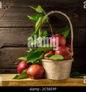 Basket with apples. Still life with ripe apples on wooden background in rustic style. Beautiful background with harvest of red apples. Stock Photo