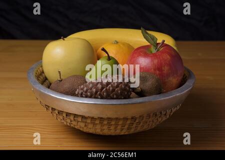 Horizontal shot of still life with some fruits in a metal bowl-like basket on a wooden table Stock Photo