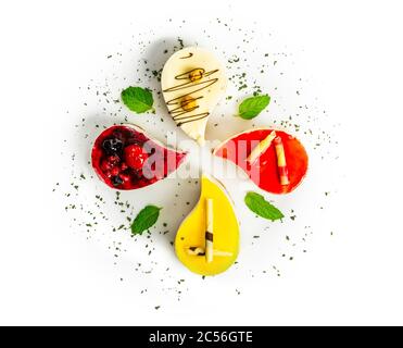 Overhead shot of four different teardrop-shaped cheesecakes on a white plate Stock Photo