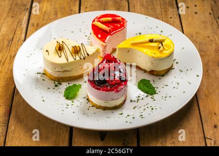 Closeup shot of four different small teardrop-shaped cheesecakes on a white plate Stock Photo