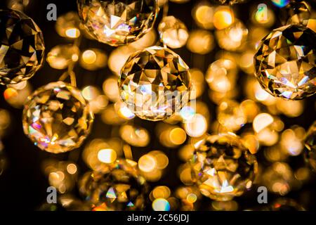 Abstract crystal chandelier pendant or crystal faceted balls background in golden tone on black Stock Photo