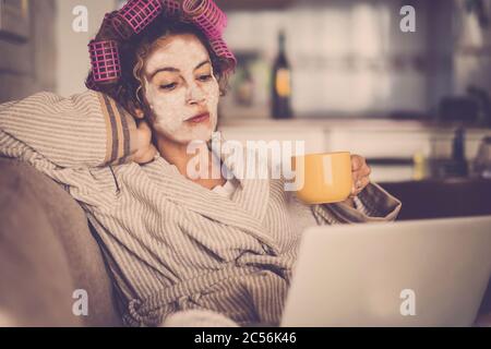 People lockdown at home concept for coronavirus emergency worldwide pandemic - woman at home with beauty face mask looking the web with laptop for new Stock Photo