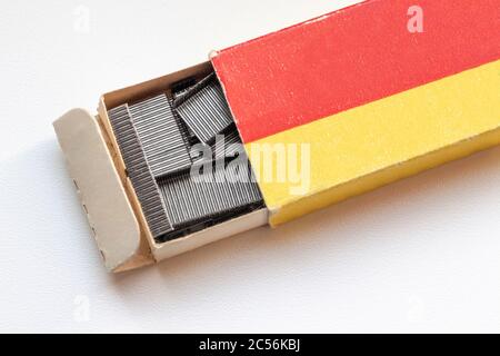 Staples for an office stapler in an open box on a white table. Stock Photo