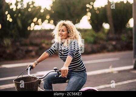Beautiful and cheerful adult young woman enjoy bike ride in sunny urban outdoor leisure activity in the city - happy people portrait - trendy female o Stock Photo
