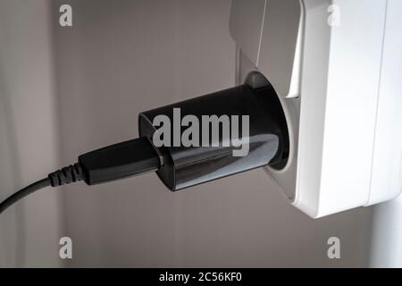 Black charging for a smartphone in a white outlet. Stock Photo