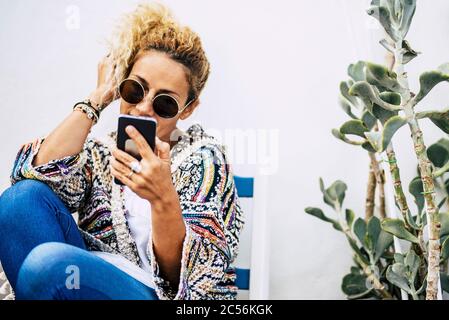 Happy trendy fashion young beautiful woman use modern technology phone to call friends - people and internet devices outdoor - white background and gr Stock Photo