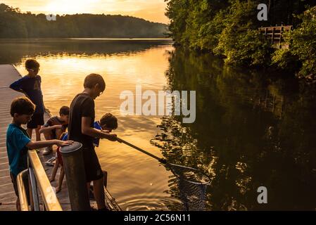 Boys fishing from a lake dock at the Fort Yargo State Park campground in Winder, Georgia. (USA) Stock Photo