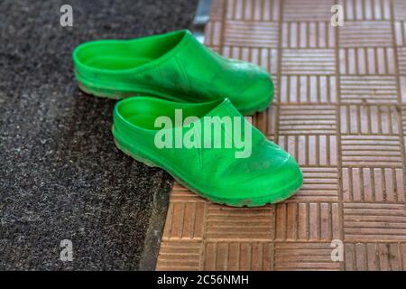 Green rubber slippers are standing on the porch of the house. Stock Photo