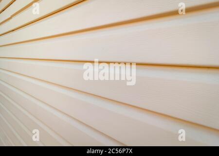 Part of the wall of a private house covered with plastic beige siding. Stock Photo
