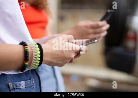 Closeup of two young people using cellphones under the sunlight with a blurry background Stock Photo