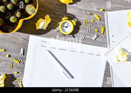 Weekly planner with alarm clock and office supplies. Business planning, workplace Stock Photo