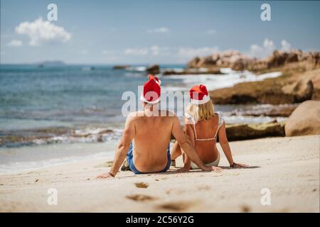 Tanned couple wear Santa Claus hat on tropical beach - Christmas or New Year's escape vacation concept. Stock Photo