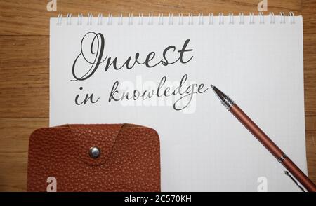 Conceptual hand writing showing Invest in Knowledge. Brown leather wallet and pen on copybook. Business education concept Stock Photo
