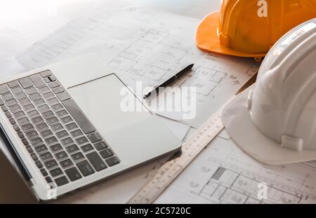 Close-up of blueprints with sketches of projects, laptop, helmet and some mechanical tools. Stock Photo