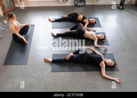 Yoga instructor and students practicing supine spinal twist in yoga class Stock Photo