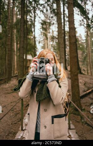 Portrait woman using retro camera in woods Stock Photo