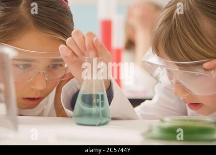 Curious junior high school girl students examining liquid in science beaker Stock Photo