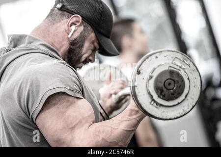 strong bearded man in hoodie lifting heavy barbell deadlift among people  indoors gym sport training workout Stock Photo - Alamy