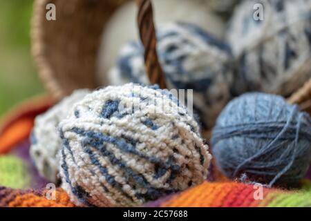 Close-up of white-blue fluffy balls of wool yarn in a basket on a natural background. Yarn for knitting. Items for female needlework. Stock Photo