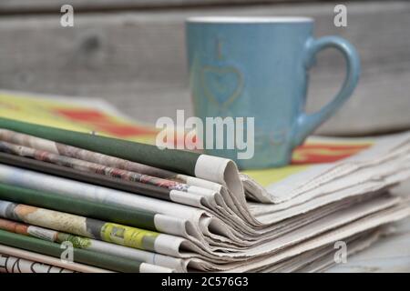 Closeup of the stack of newspapers with a cup of coffee isolated on a wooden surface Stock Photo