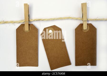 Empty copy space tags hanging on the rope with wooden clothespins on white background Stock Photo
