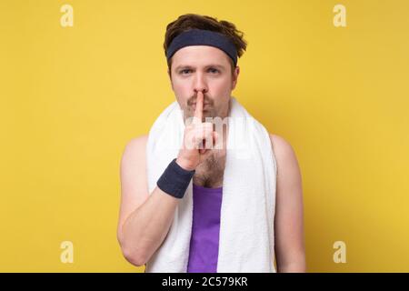 male sportsman keeps finger on lips, asks not tell secret information Stock Photo