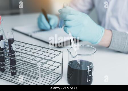 Lab Note Recording Scientist recording making note on book with his findings test tube in ...
