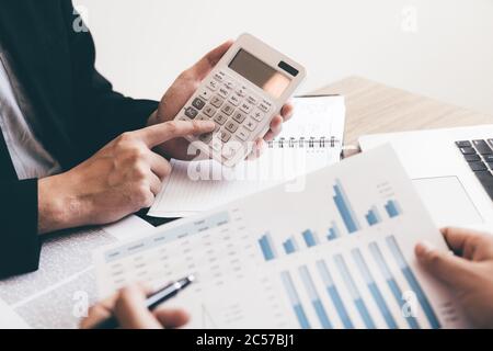 Colleagues are showing numbers in calculator that are calculated and speaking to employees that the results must meet the goals. Stock Photo
