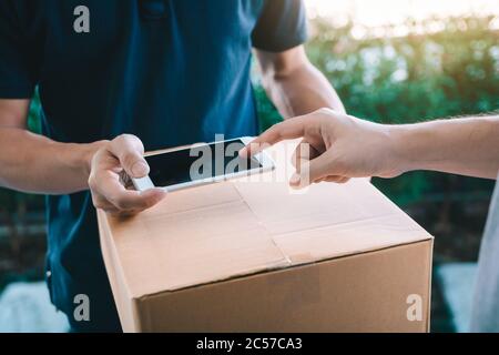 Close up of hand asian man using smartphone pressing screen to sign for delivery from the courier at home. Stock Photo