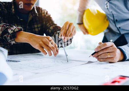 Engineering partnerships working with blueprints and discussing project together at the meeting in the office. Stock Photo
