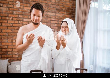 Muslim couple wear ihram praying open their arm wearing ihram before going for umrah and hajj Stock Photo