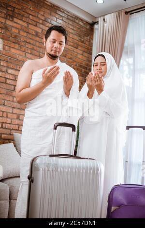 Muslim couple wear ihram praying open their arm wearing ihram before going for umrah and hajj Stock Photo