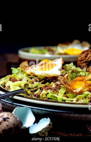 Pan dish, pointed cabbage, minced beef, fried egg from quail eggs Stock Photo