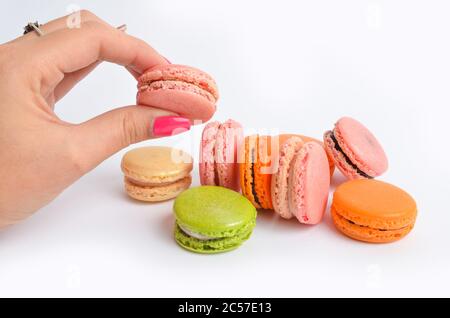 Closeup of colorful macaroon in a female hand against a white background Stock Photo