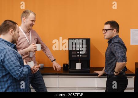 Happy diverse colleagues have fun at lunch break in office, smiling multiracial employees laugh and drinking coffee. Stock Photo