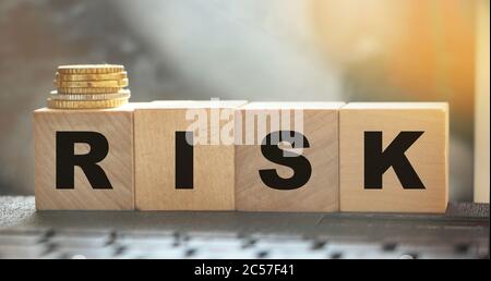 Risk Word On wooden Blocks Arranged Behind computer keyboard and stack of coins. Risky investment business concept Stock Photo