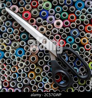 Top view of the box with colored threads on which are large scissors. Sewing industry Stock Photo
