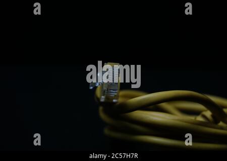 Closeup shot of a yellow ethernet cable isolated on a black background Stock Photo