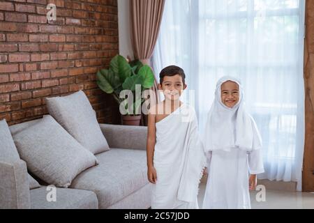 cute little kid wearing muslim ihram clothes and dress holding hand and ...